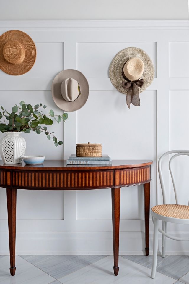 Wood furniture piece with hanging hats and chair in a natural looking interior design